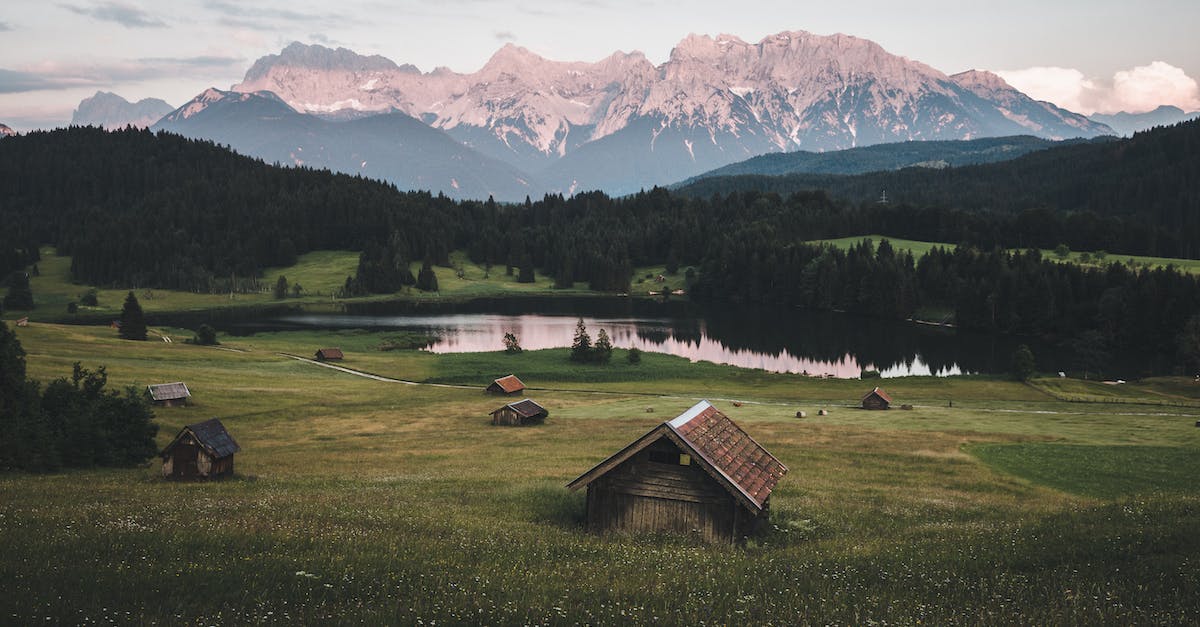 Brown Wooden House on Green Grass Field Near Green Trees and Mountains