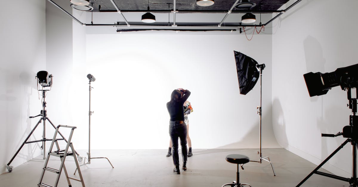 Back view of unrecognizable professional photographer taking photo of anonymous model in modern light studio